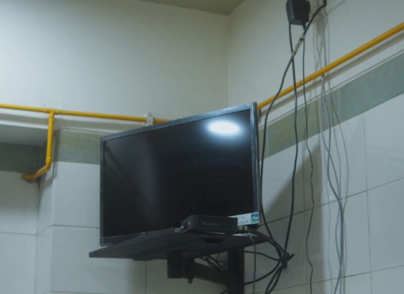 prikaz televizora na polici sa mnogo kablova po zidu