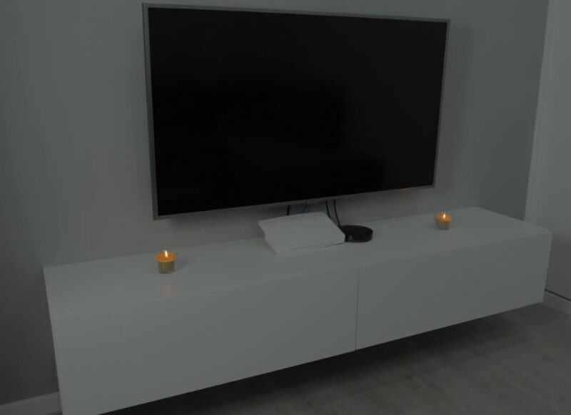 prikaz televizora i komode ispod tv-a na kojoj je ruter i sveće